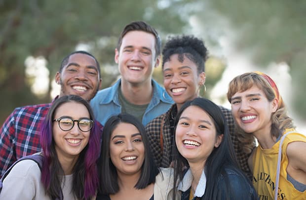 Diverse group of teens standing outside and smiling at the camera