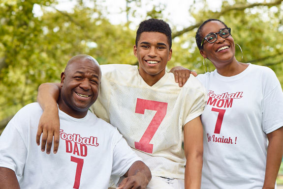 Two parents and teen, all wearing football jerseys